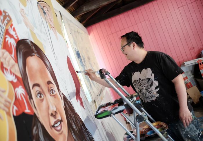 Artist Alex Chiu painting a mural panel